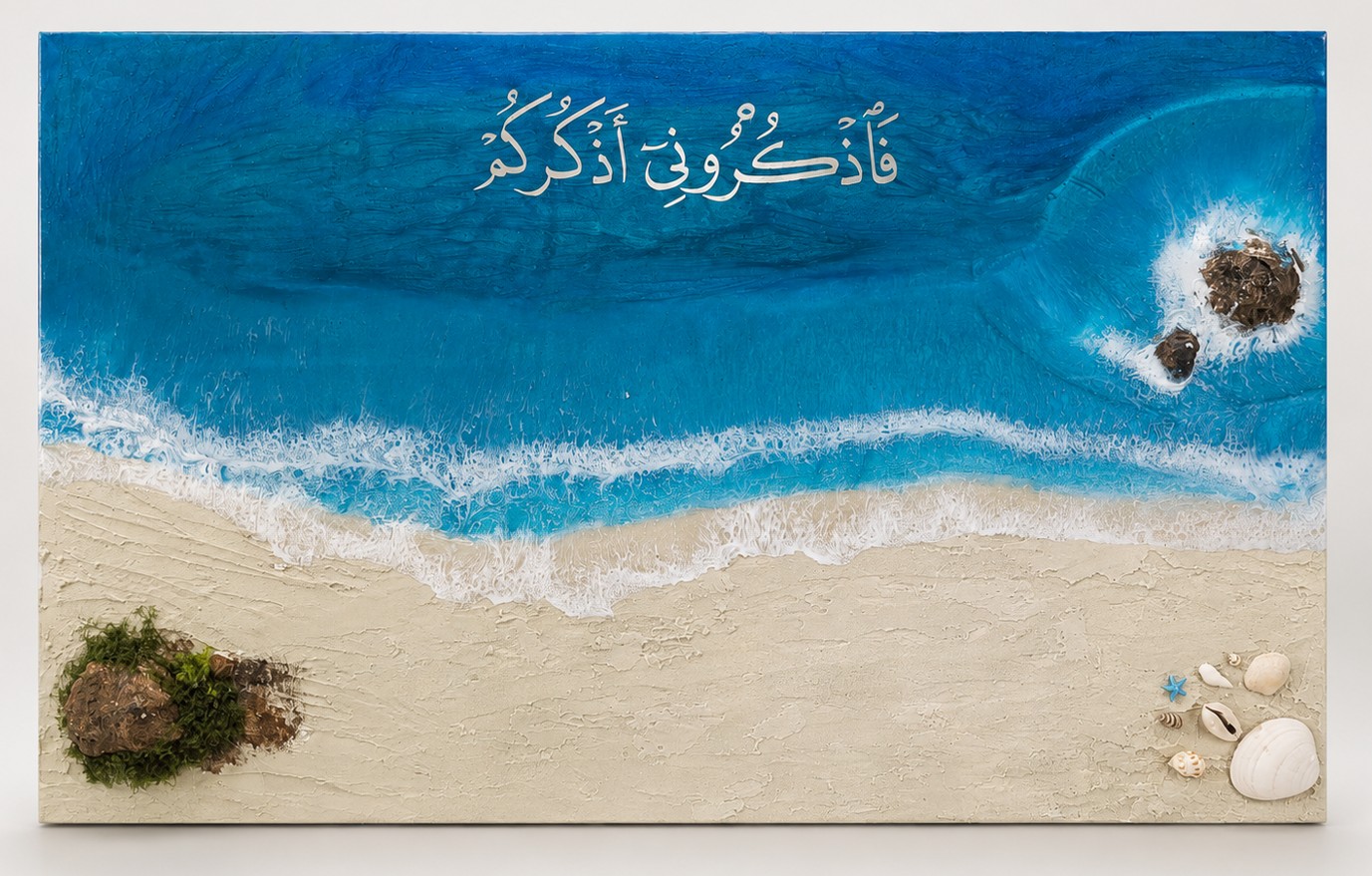 Front view of Ocean Remembrance resin wall art with blue ocean waves, a textured sandy shore, shells, natural accents and Arabic calligraphy.